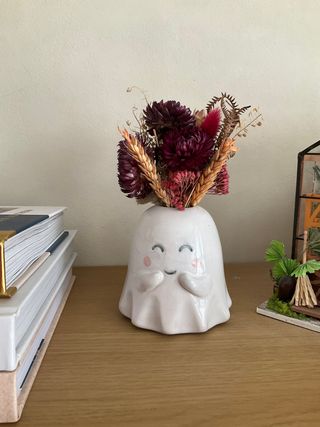 Little vase in the shape of an ghost trying to hide their gentle smile with their hands.