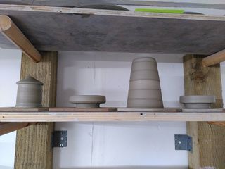 Parts of a lighthouse in wet clay, on their bats, on a shelf: top, balcony, tower, another balcony. 
