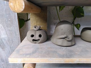 Two clay decorations: a carved pumpkin and a little ghost drinking tea.