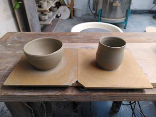 Two thrown stoneware vessels on their bat: a small round bowl and a small bulbous cup body.
