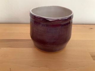 Angled planter with a thick rectangular rim at the top, glazed white inside dripping on a dark purple outside.