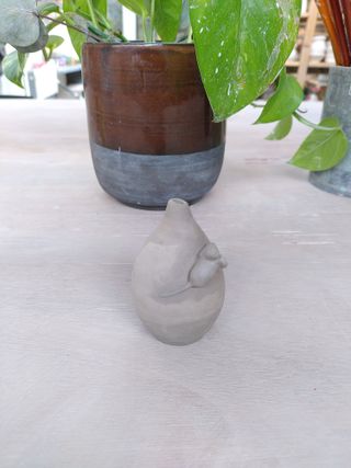 Back picture of a leather dry tiny bulbous vase with a little mouse climbing its collar