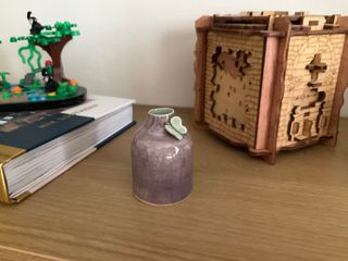 A tiny light-purple bottle with a light-blue-green butterfly on its short collar.
