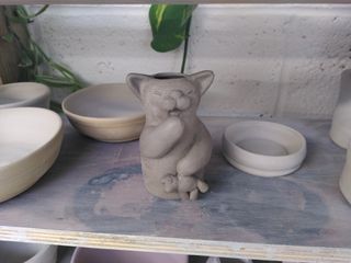 Sculpted vase in the shape of a yawning cat holding a teddy-mouse.
