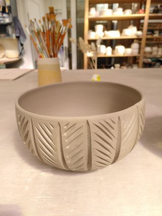 A carved bowl with carved marks creating vertical sections with alternating diagonal hatches.