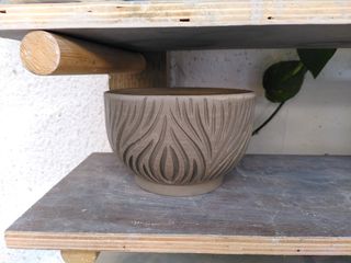 A bowl with organic, long vertical-ish carvings on its surface