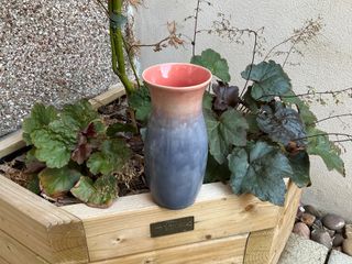 A vase glazed in a dark purplish blue turning into a pink at the top of the vase, continuing pink inside.