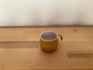 A little bubbly espresso cup, whose inside white glaze overflows on the outside at the top.