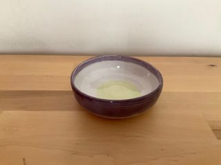 Short straight bowl with a dark purple outside glaze folding over a white inside glaze with brush marks of faint green at the bottom.