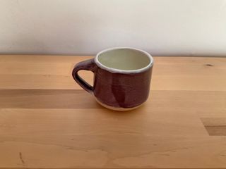 Tiny purple cup, glaze white inside and with a faint green band overlaid at the top.