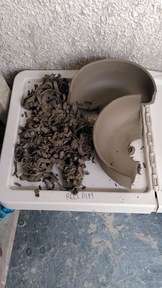 Clay trimmings and two halves of a bowl on a reclaim box