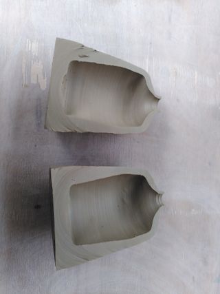 Two halves of a vase laid on a table, exposing the thick bottom and bottom of the wall