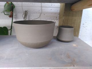 A flared bowl and mountain shaped cup on a board, both trimmed.