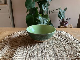 A bowl with a curvy foot, glazed light green inside and dark green outside.
