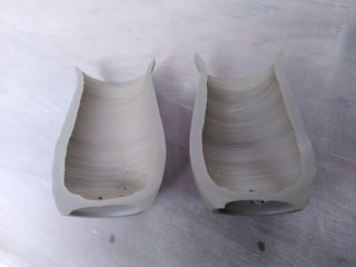 Two halves of a clay vase lying on a table, exposing the wall's thickness