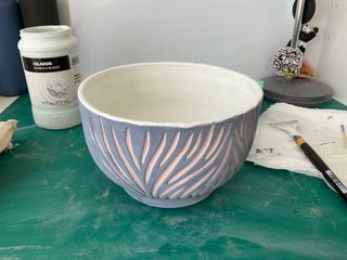A carved bowl with glaze painted on, light red in the carvings, blue on the surface and white inside
