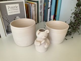 Two planters and a vase shaped as a bear inspecting a butterfly with a magnifying glass, all bisque fired and ready to decorate.
