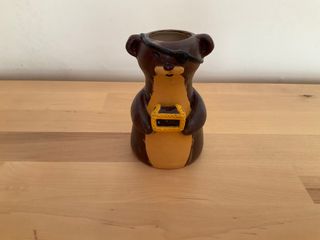 Little vase in the shape of a dark brown weasel with an eye patch holding a little treasure chest.

**Note**: Outside glaze is very thin and a little patchy. Inside is good, though and the vase is watertight.