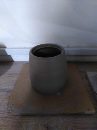 A curvy pot with a little gallery to support a lid at its top.
