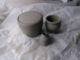 Leather dried ceramics: A curvy pot with an inset flat lid, a cauldron with 3 feet and a bottle-shaped tiny bud vase.
