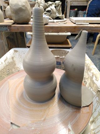 A double gourd vase on the wheel after throwing next to half of a leather hard double gourd vase, of which it kinda matches the proportions.
