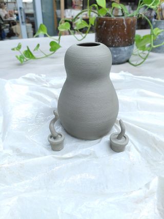 A clay vase with two miniature plant pots next to it.