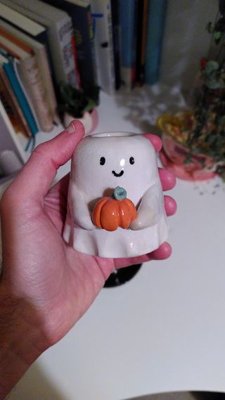 A vase shaped as a kawai ghost holding a pumpkin.
