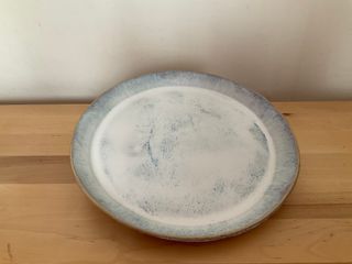 A plate with an angled rim, glazed white with blue marks.