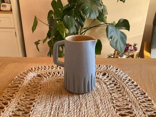 
A light matt blue jug with tiny brown speckles, with a beige inside
