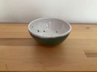 Little bowl lifted by a concave raw ceramic foot, glazed light teal outside and white with teal spots and inside.