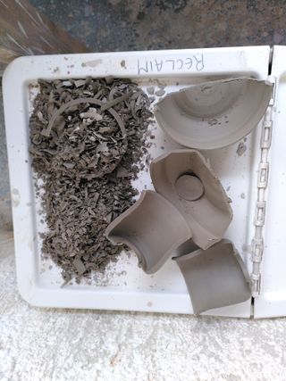 Reclaim clay box packed with leather hard halves of ceramic pieces and clay shavings