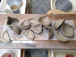 Halves of leather hard clay forms spread on a board