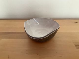 Bowl flattened into a triangle, with a white inside glaze and dark outside glaze.