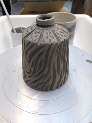A carved bottle-shaped clay form
