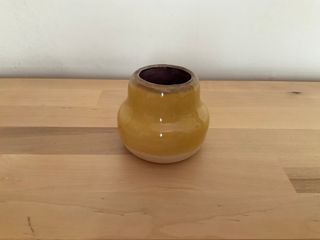 Tiny yellow vase with a purple inside, overlaid a little on the top rim. 