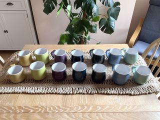 A series of 14 mugs (7 pairs: yellow, green, light teal, blue, dark blue, purple, grey) created as gifts for an upcoming celebration.