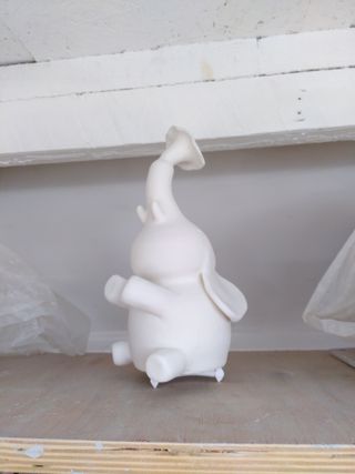 An elephant clay sculpture, happily blowing water from it's trunk, covered in a white coat of unfired transparent glaze.