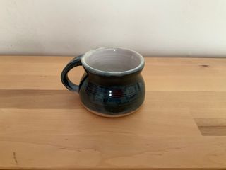 Bulbous dark blue cup (with a thin raw ceramic at its bottom), white glazed inside with a hint of light green glaze over the rim.