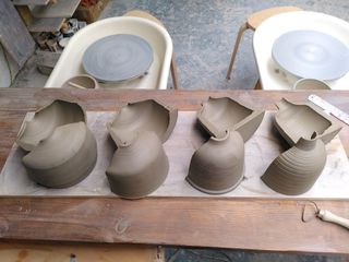 Trimmed clay forms cut in half on a shelf
