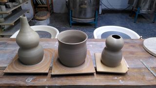 A double gourd vase, bulbous planter and 'head and body' vase, on their bats after throwing.
