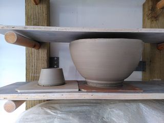 A large curvy bowl and small cone on their bats waiting to dry