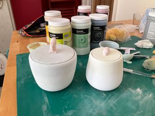 Two jars, one knobbed with a squirrel the other with a hedgehog, painted in glaze.