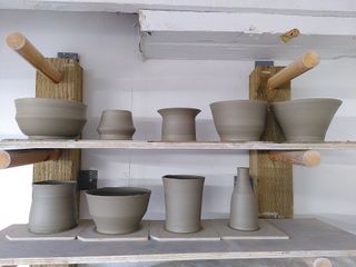 9 thrown clay forms of various shapes on their bats waiting to dry