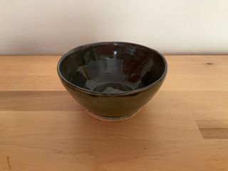 A dark bowl, glazed black inside and dark green outside.