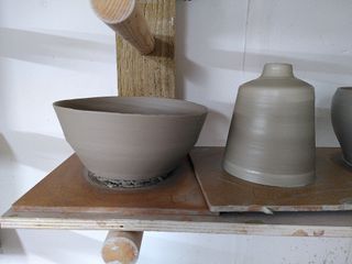 A (slightly wonky) bowl and tappered bud vase waiting to dry on their bats after throwing.