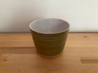 A light green planter, with two indented stripes around the top and a white inside.