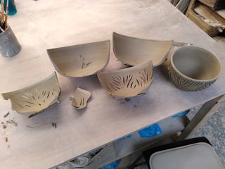 Halves of two bowls carved too deep for one and trimmed too thin at the bottom, next to a surviving carved bowl.