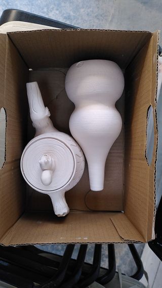 Bisque fired ceramic pieces in a cardbox: a forest themed carved teapot with a squirrel knob and a double gourd vase