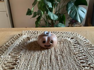 A little carved pumpkin, orange with a light purplish stem, ready to cover a candle and brighten up.