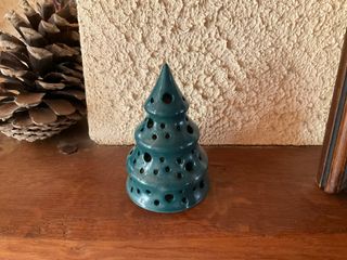 A green Christmas tree pierced of multiple holes for letting a tealight shine through.